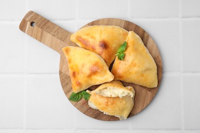 Delicious samosas and basil on white tiled table, top view