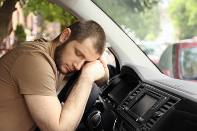 Photo of Tired man sleeping on steering wheel in his car