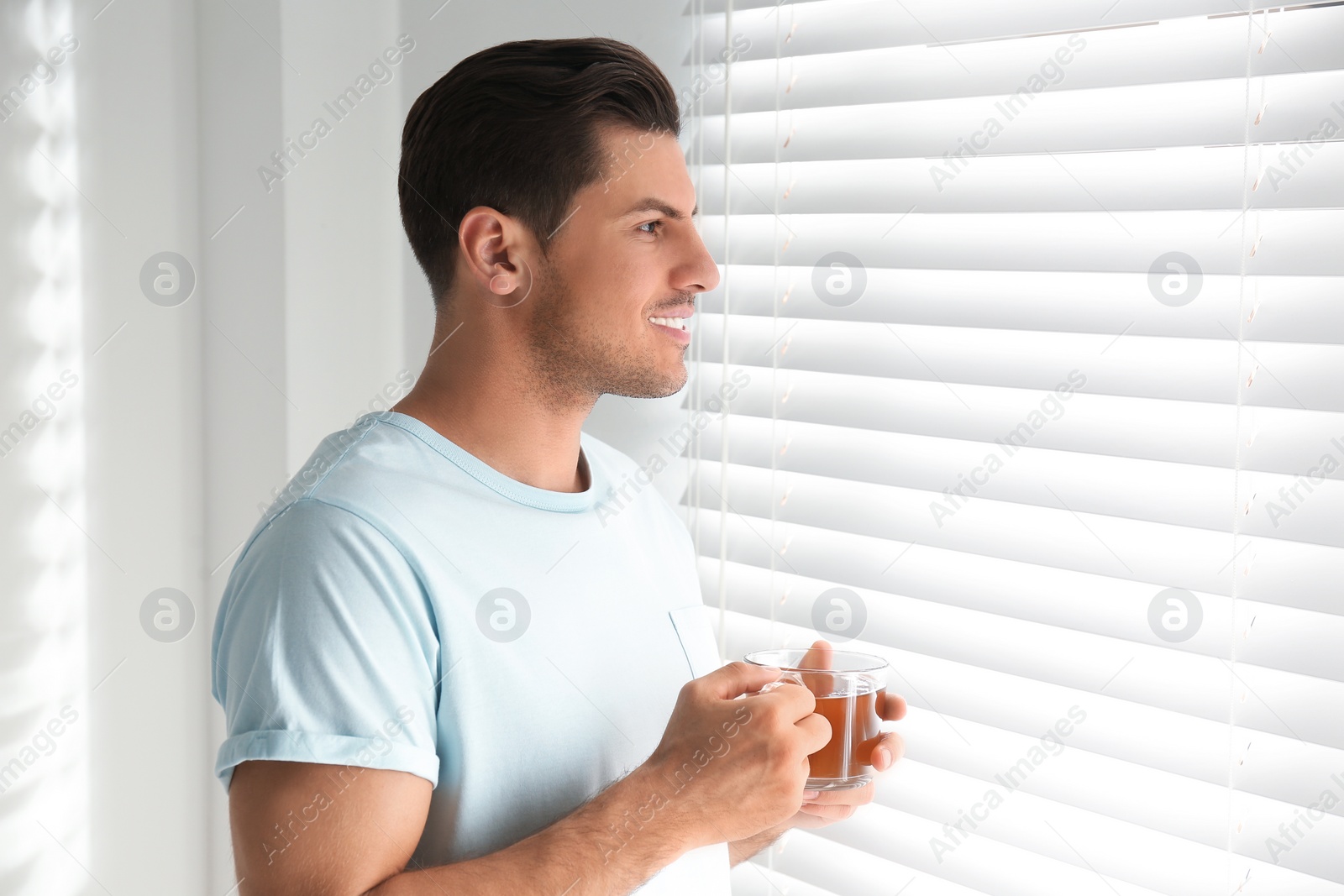 Photo of Man with cup of tea near window. Lazy morning