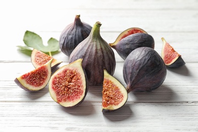 Photo of Whole and cut purple figs on wooden background