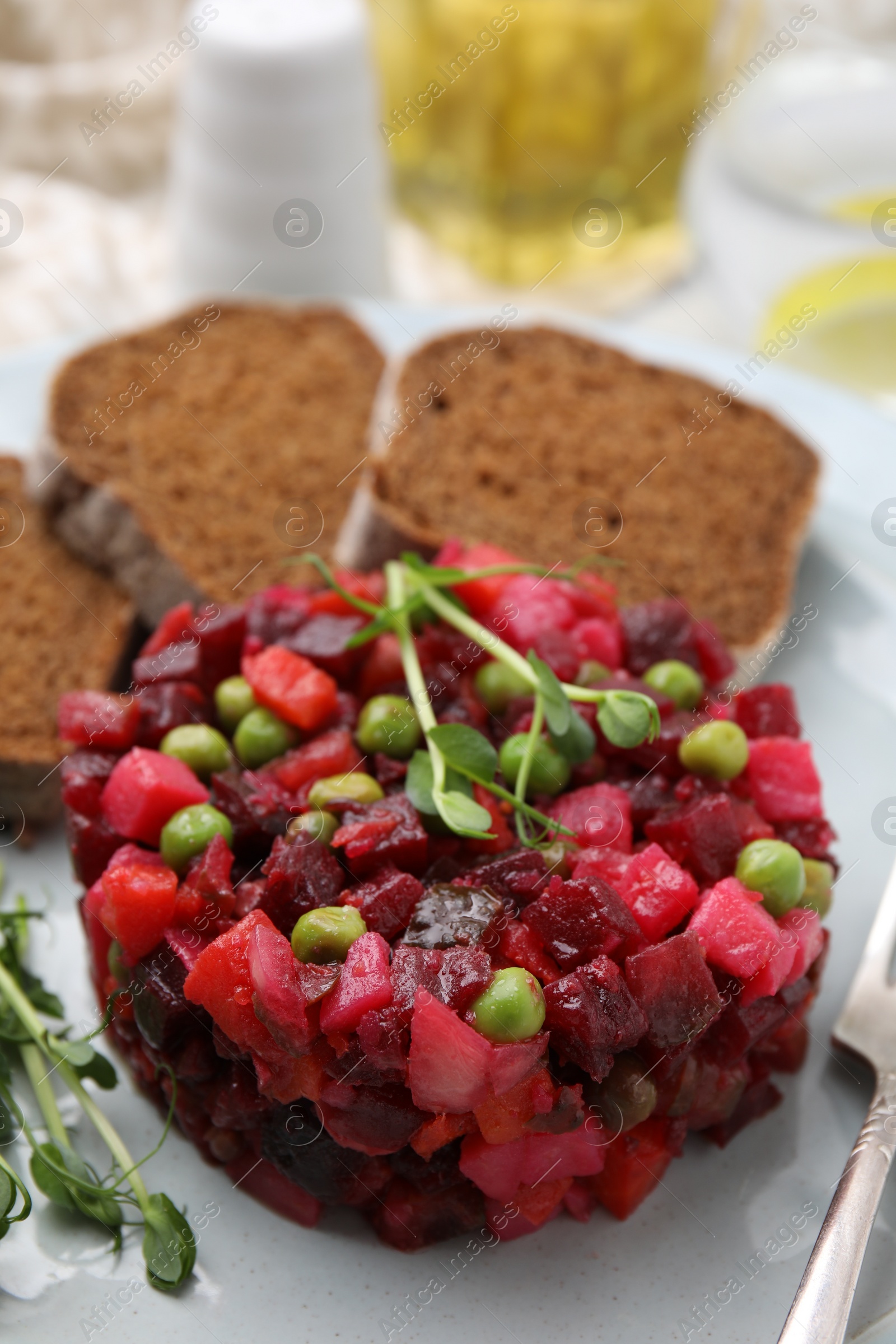 Photo of Delicious vinaigrette salad with slices of bread on white table, closeup