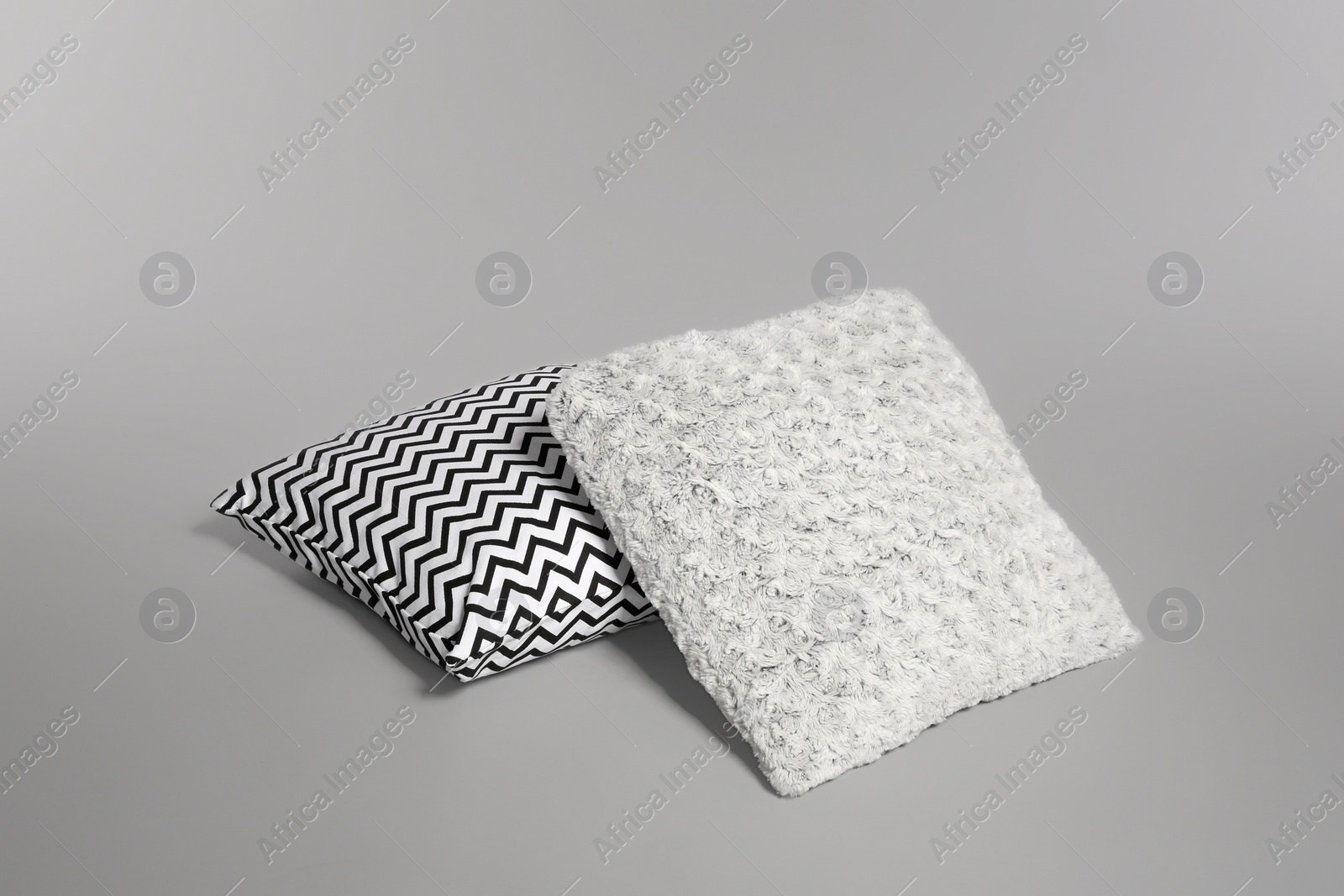 Photo of Two stylish decorative pillows on light background