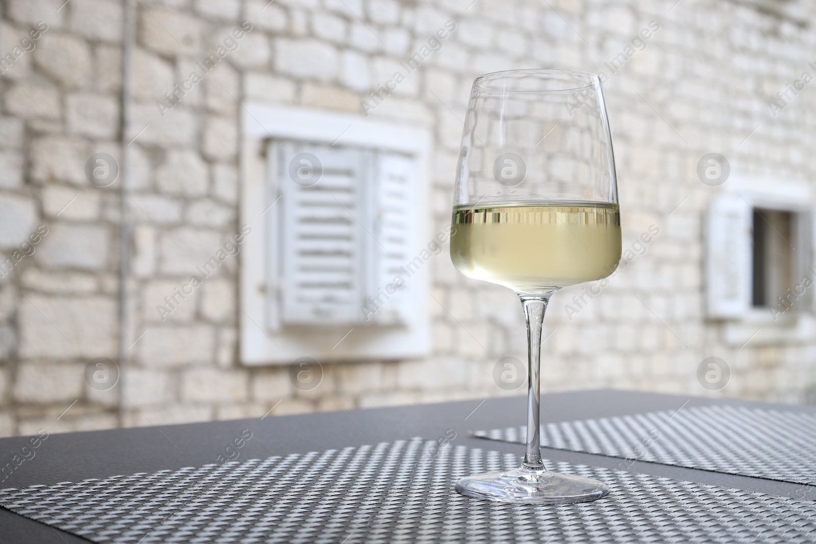 Photo of Glass of wine on black table outdoors. Space for text