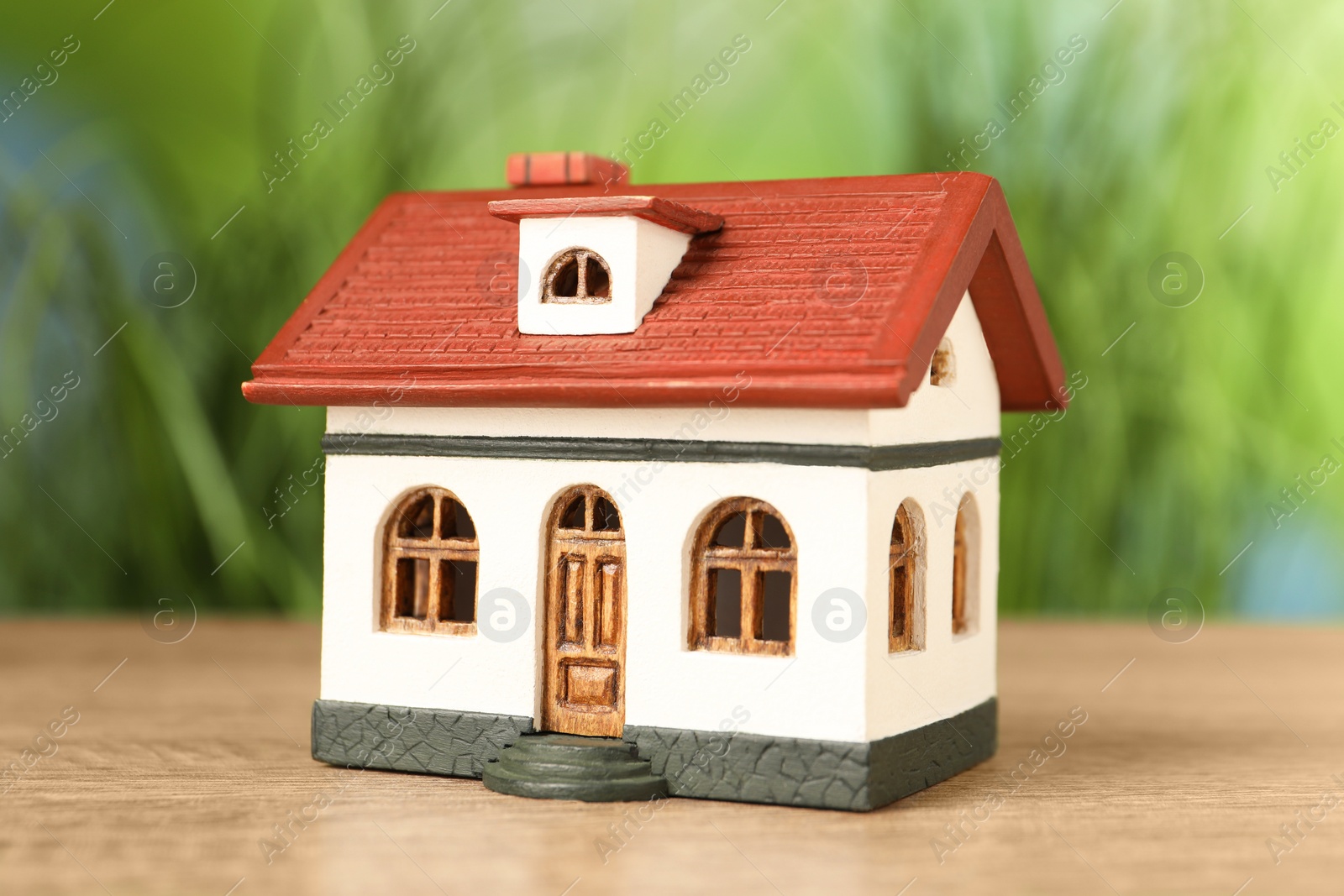 Photo of Mortgage concept. House model on wooden table against blurred green background