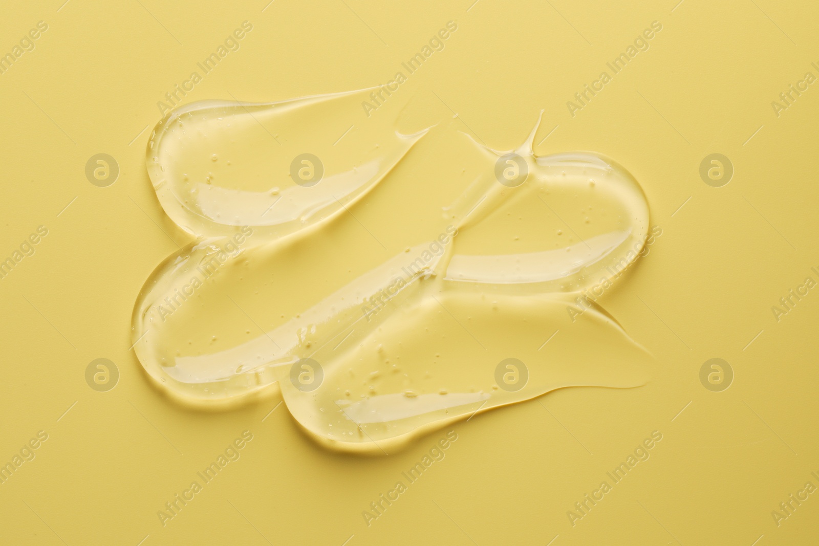 Photo of Sample of clear cosmetic gel on yellow background, top view