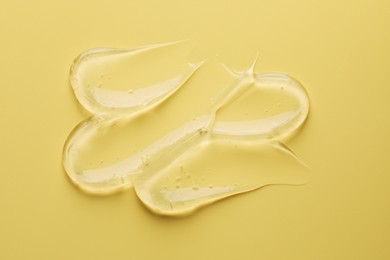 Sample of clear cosmetic gel on yellow background, top view