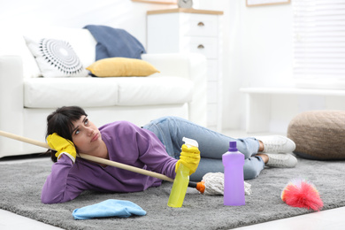 Photo of Lazy woman procrastinating while cleaning at home