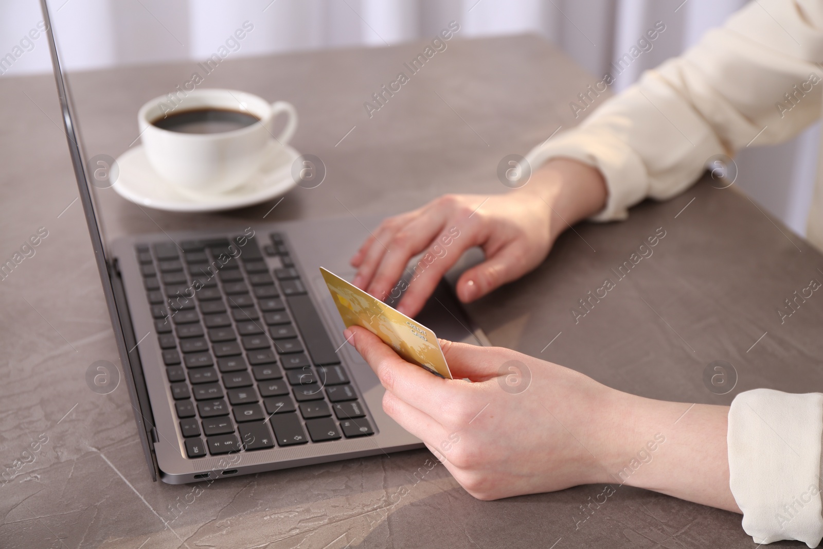 Photo of Online payment. Woman with laptop and credit card at grey table, closeup