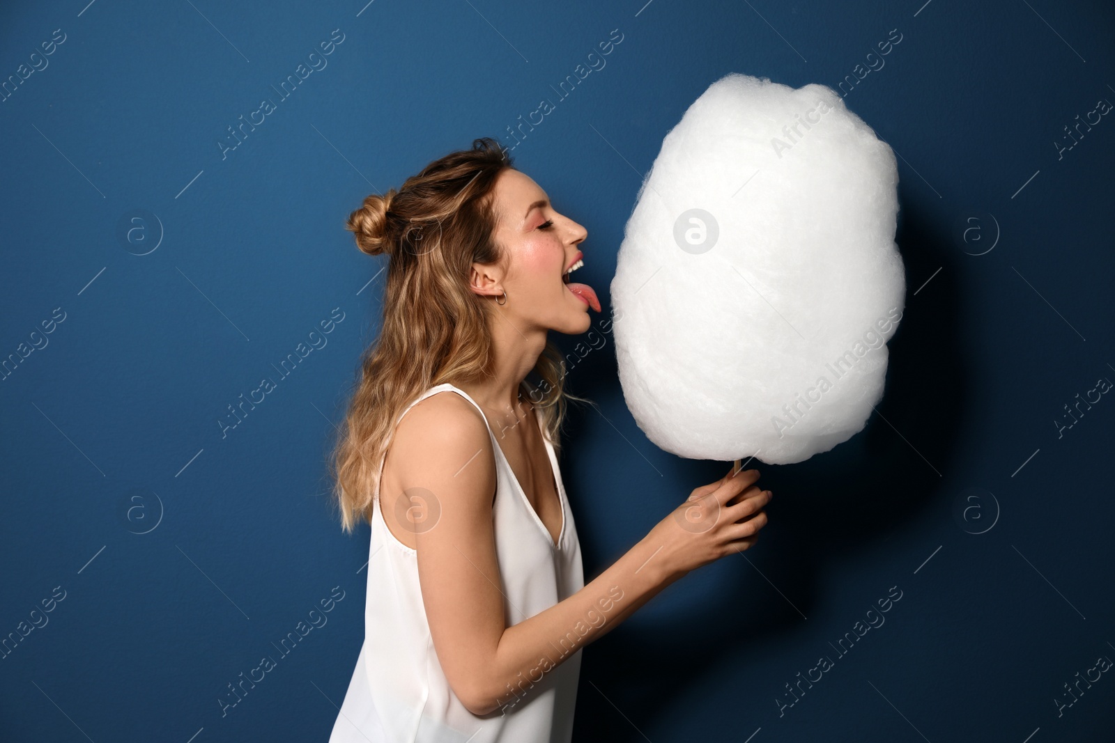 Photo of Portrait of pretty young woman with cotton candy on blue background