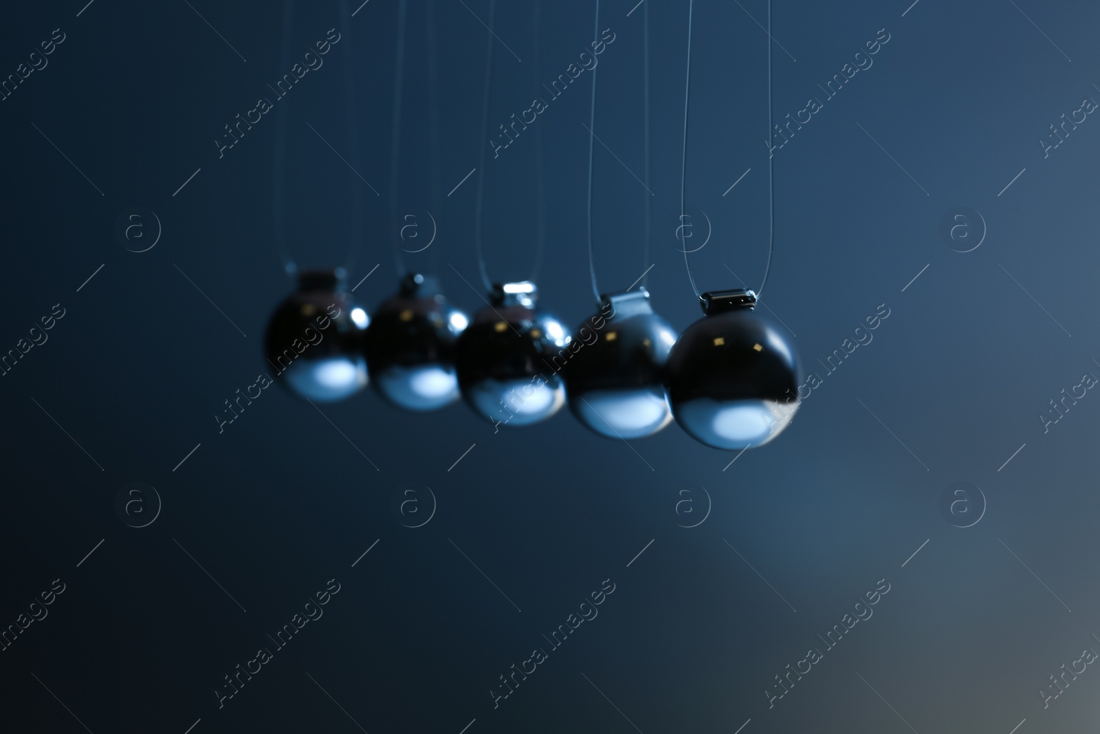 Photo of Newton's cradle on grey background, closeup. Physics law of energy conservation