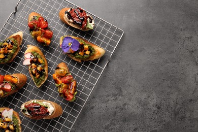 Photo of Delicious bruschettas with different toppings and balsamic vinegar on gray textured table, flat lay. Space for text