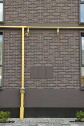 Yellow gas pipes near brick wall outdoors