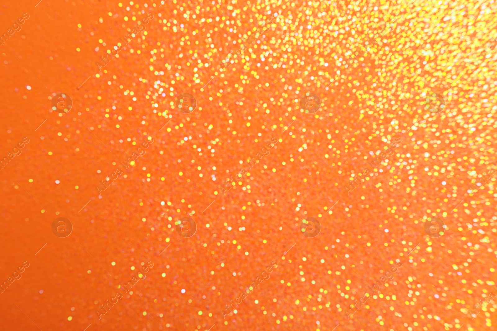 Photo of Blurred view of shiny bright glitter on orange background. Bokeh effect