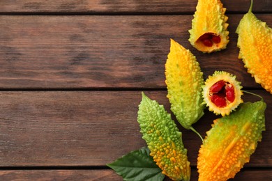 Photo of Fresh bitter melons on wooden table, flat lay. Space for text