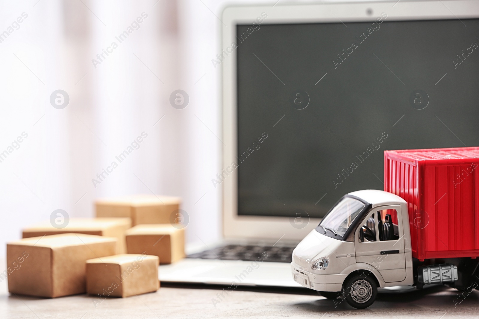 Photo of Toy truck near laptop on table. Logistics and wholesale concept