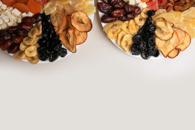 Plates with different dried fruits on white background, top view. Space for text