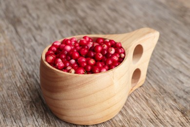 Photo of Cup with tasty ripe lingonberries on wooden table, closeup