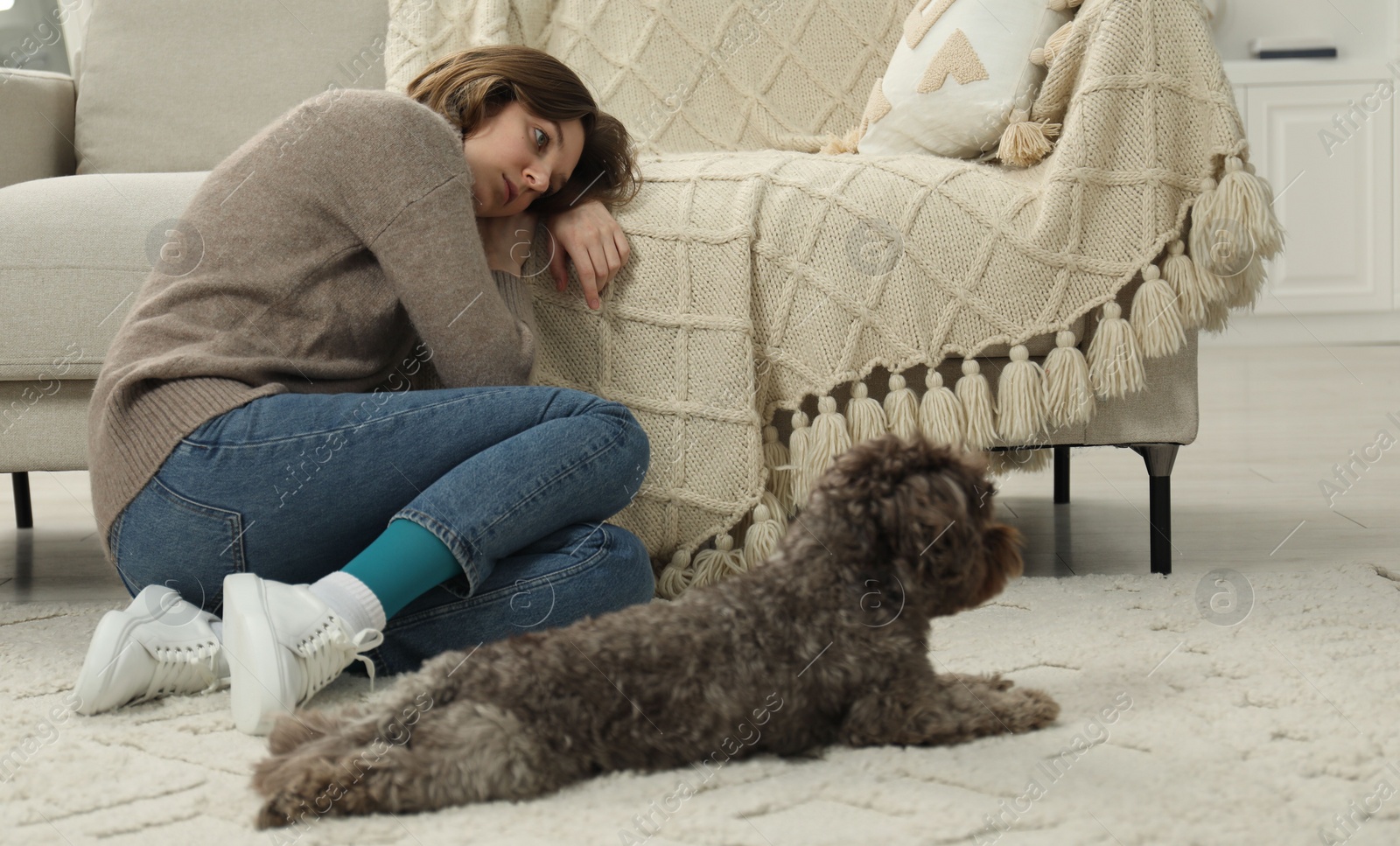 Photo of Sad young woman and her dog sitting on floor at home