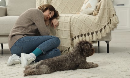 Sad young woman and her dog sitting on floor at home