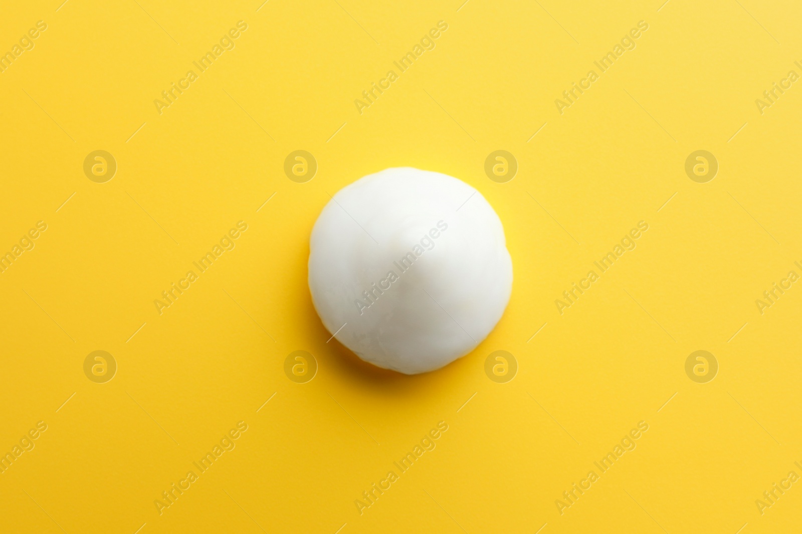 Photo of Sample of face cream on yellow background, top view