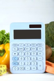 Photo of Calculator and food products on white wooden table. Weight loss concept