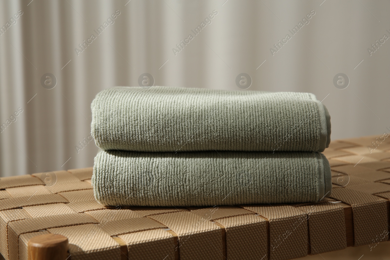 Photo of Soft towels on wicker bench indoors, closeup