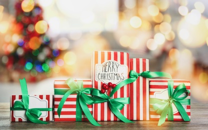 Image of Christmas gift boxes on wooden table in room, bokeh effect