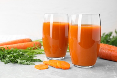 Photo of Glasses of drink and carrots on light table, space for text