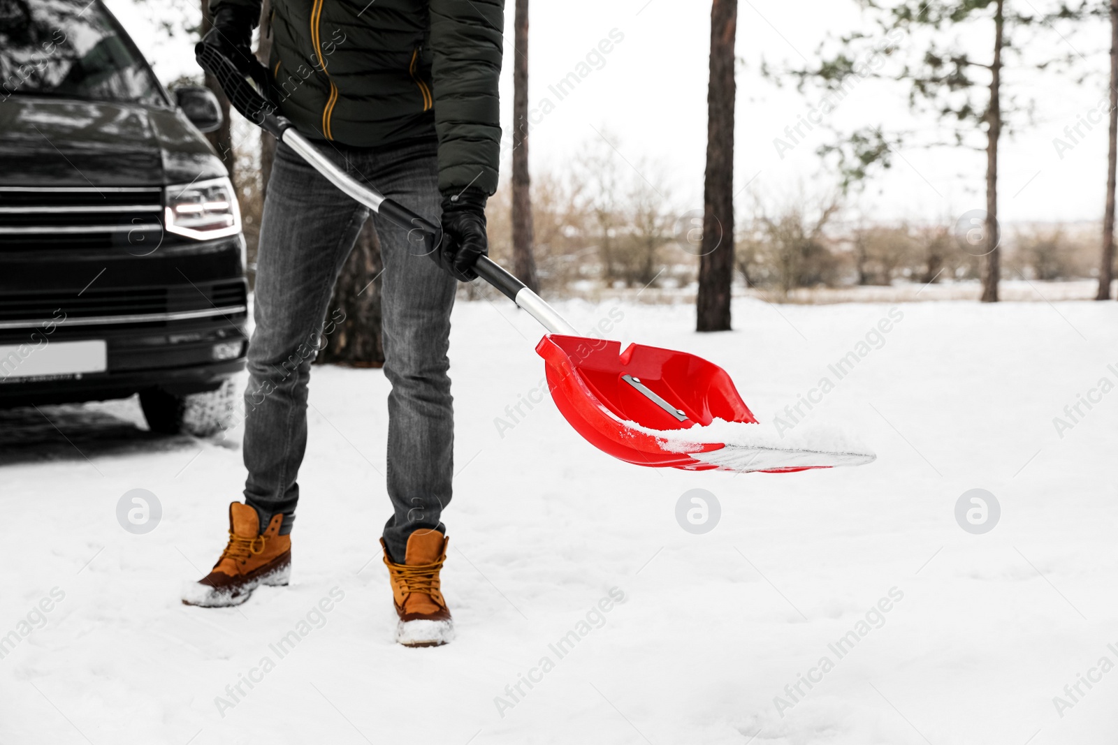 Photo of Man removing snow with shovel near car outdoors on winter day, closeup