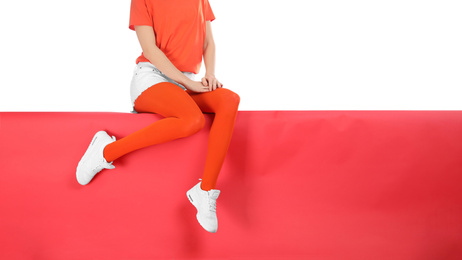 Photo of Woman wearing red tights and stylish shoes sitting on color background, closeup. Space for text