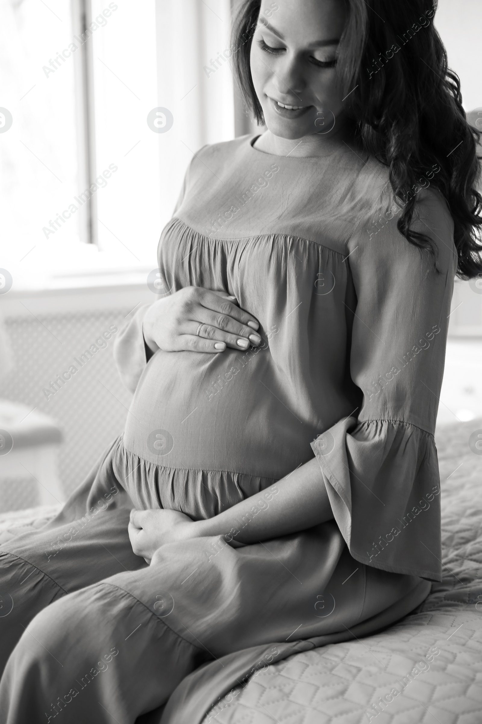 Photo of Young pregnant woman in bedroom, black and white effect