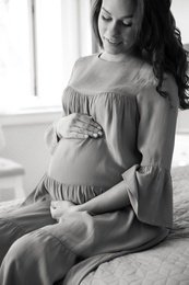 Young pregnant woman in bedroom, black and white effect