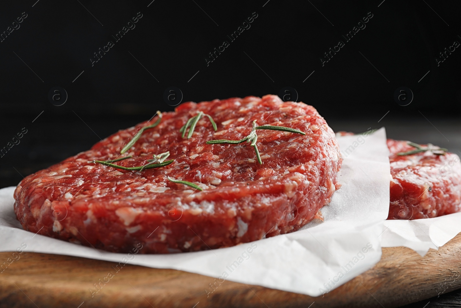 Photo of Raw meat cutlets for burger on wooden board, closeup