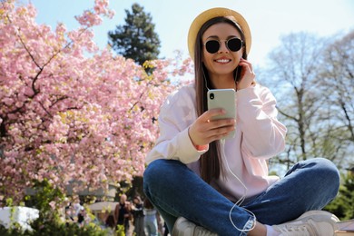 Young woman listening to audiobook in park