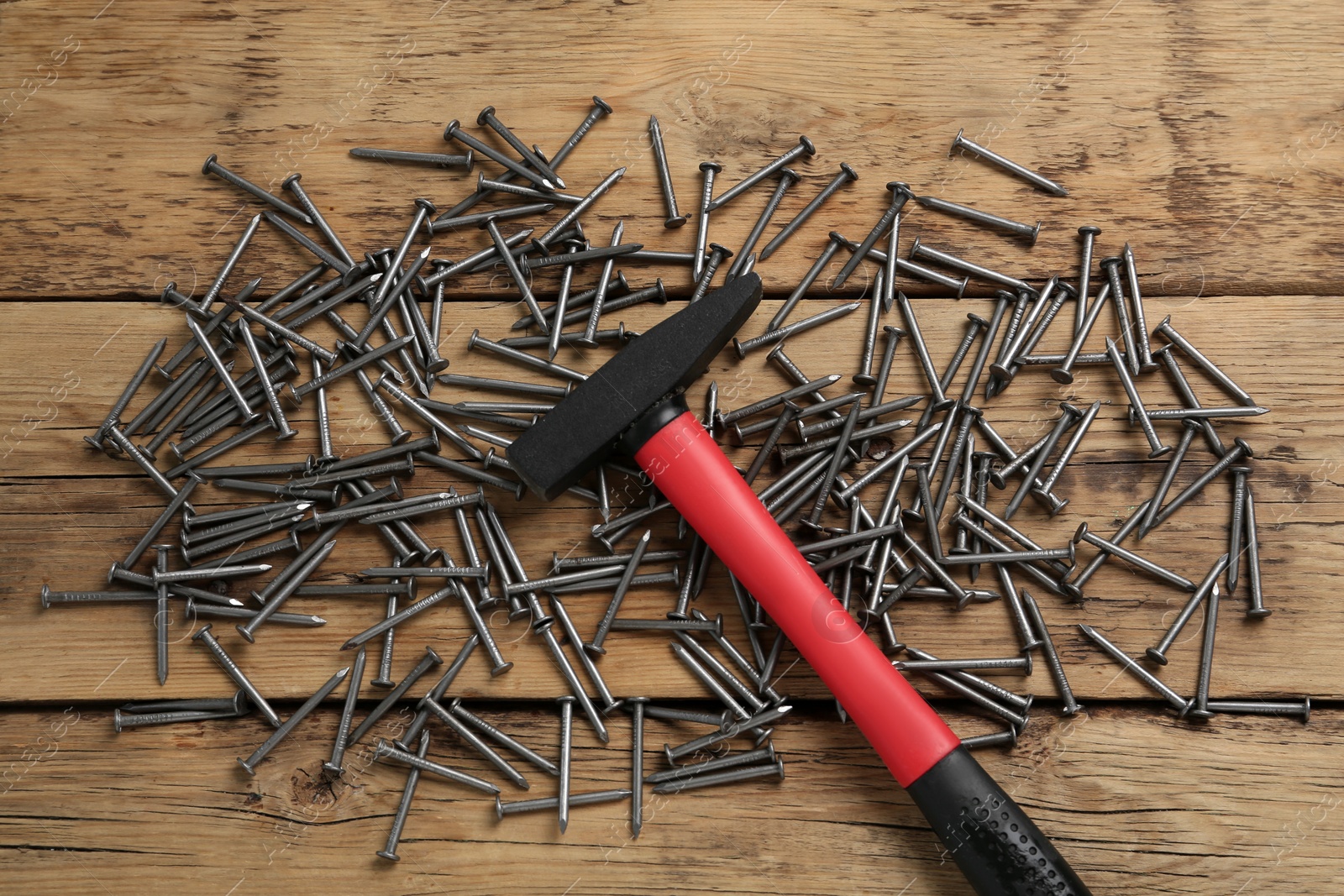 Photo of Hammer and metal nails on wooden table, flat lay