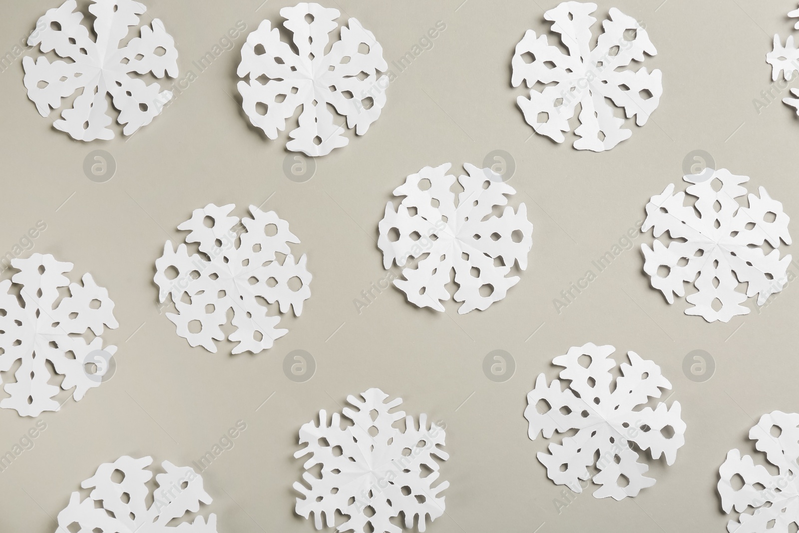 Photo of Many paper snowflakes on light grey background, flat lay