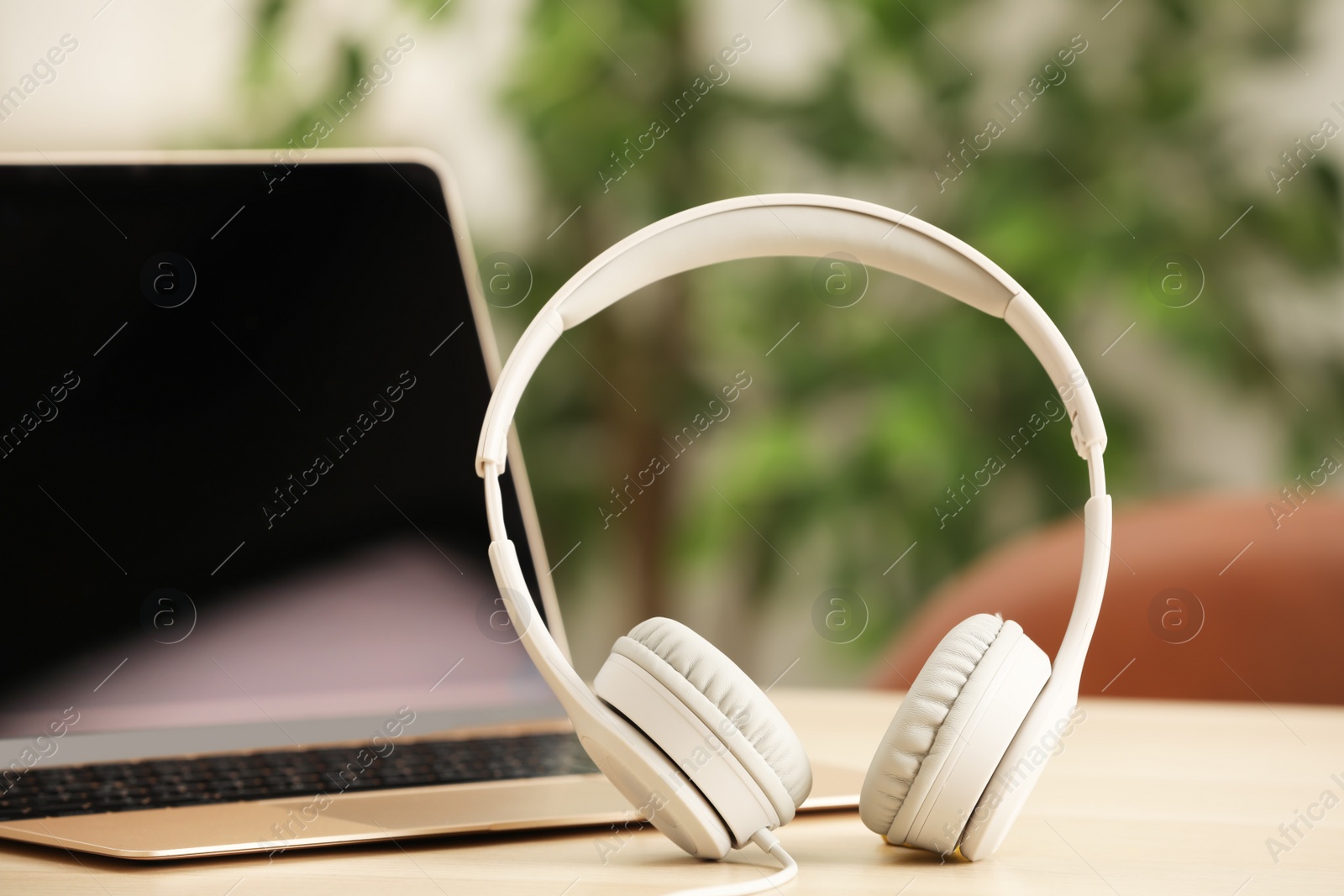 Photo of Modern headphones and laptop on table indoors