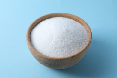 Photo of Organic white salt in bowl on light blue background