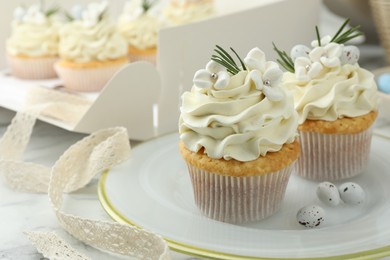 Photo of Tasty Easter cupcakes with vanilla cream on white table