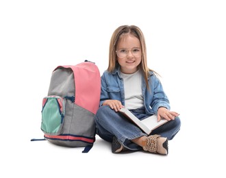 Photo of Cute little girl with book and backpack on white background