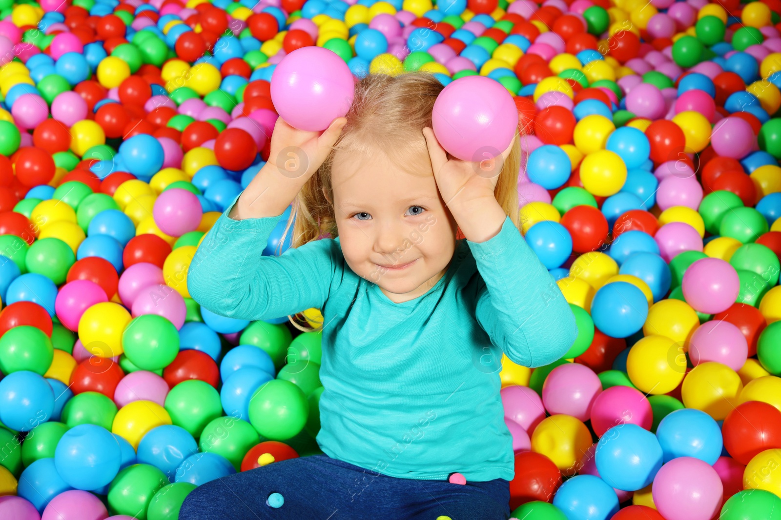 Photo of Cute child playing in ball pit indoors