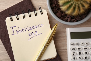 Photo of Notepad with phrase Inheritance Tax, cactus and calculator on wooden table, flat lay