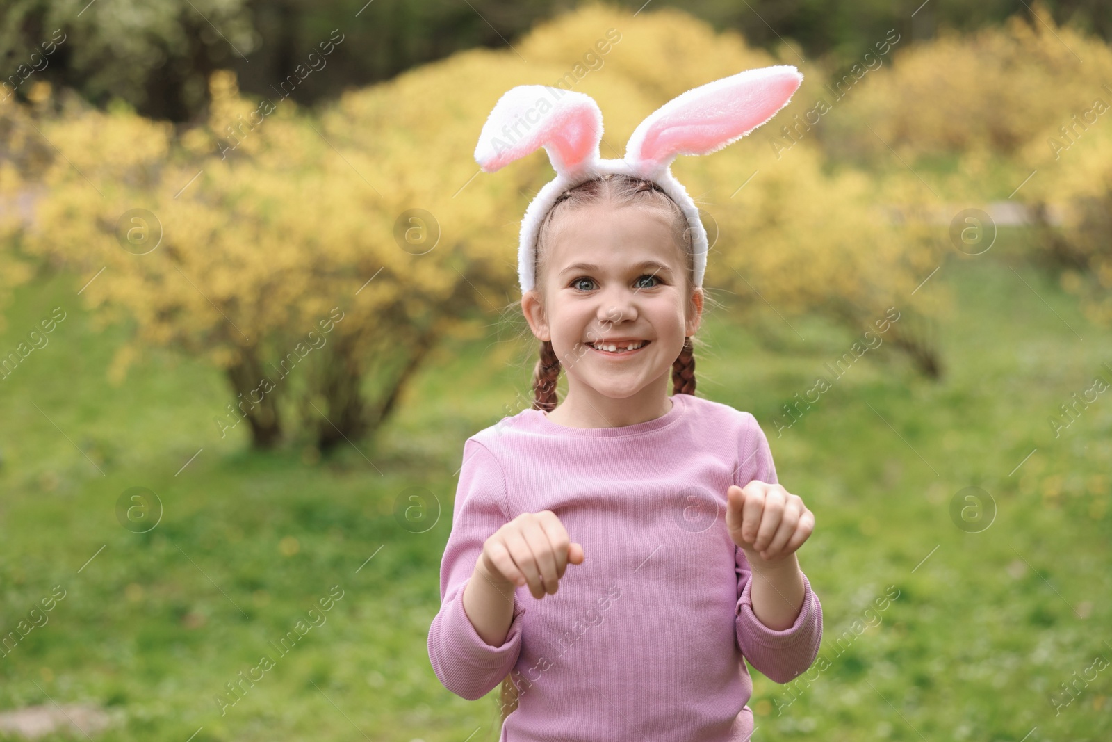Photo of Easter celebration. Cute little girl with bunny ears outdoors, space for text