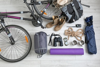 Photo of Flat lay composition with sleeping bag, bicycle and camping equipment on wooden background