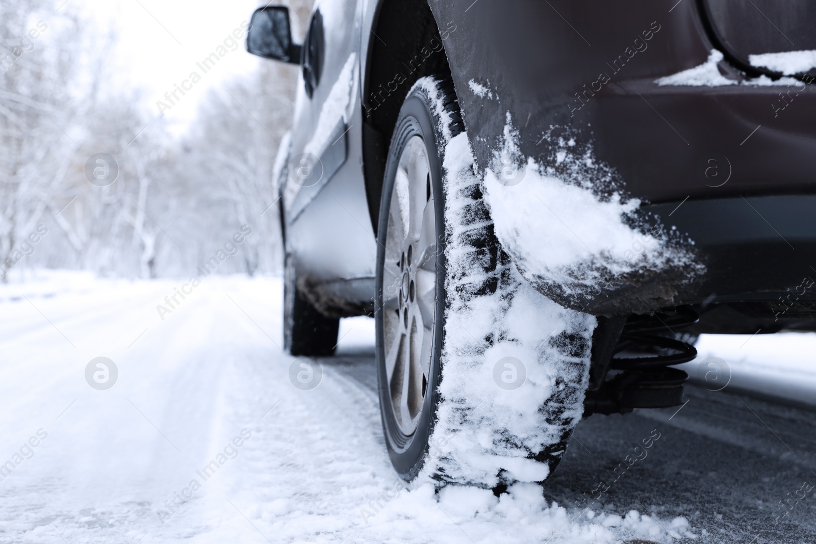 Photo of Modern car with winter tires on snowy road, closeup