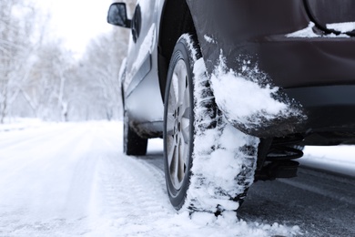 Photo of Modern car with winter tires on snowy road, closeup