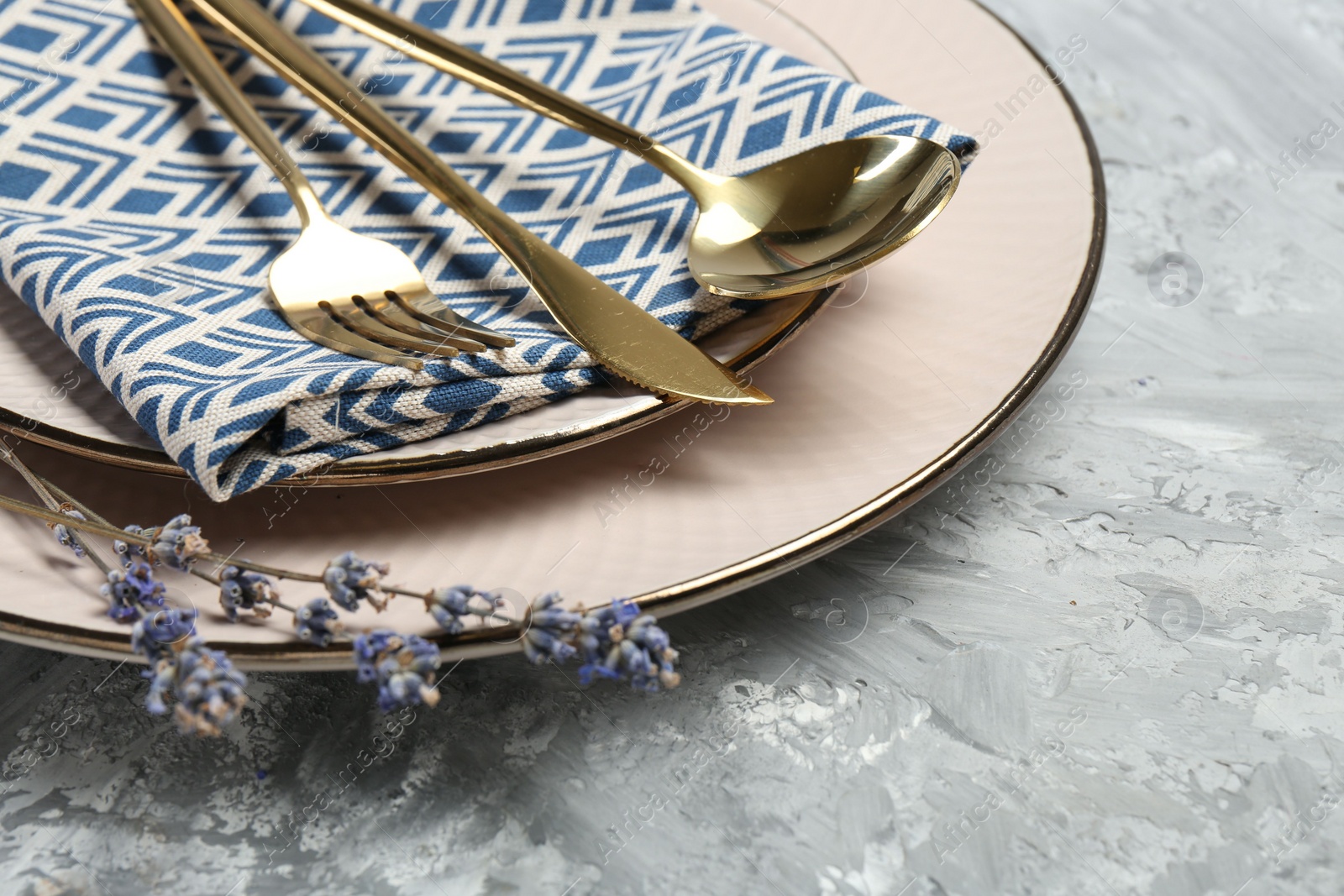 Photo of Clean plates, cutlery, napkin and lavender flowers on light grey textured table, closeup