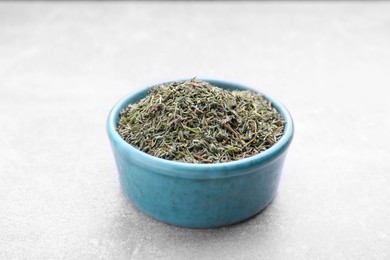 Photo of Bowl with dried thyme on grey table, closeup