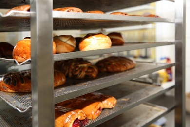 Rack with fresh pastries in bakery workshop, closeup