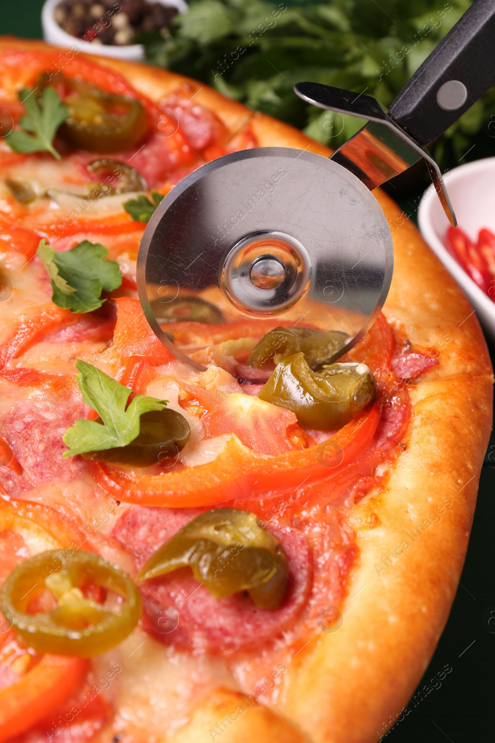 Photo of Cutting delicious pizza Diablo at table, closeup